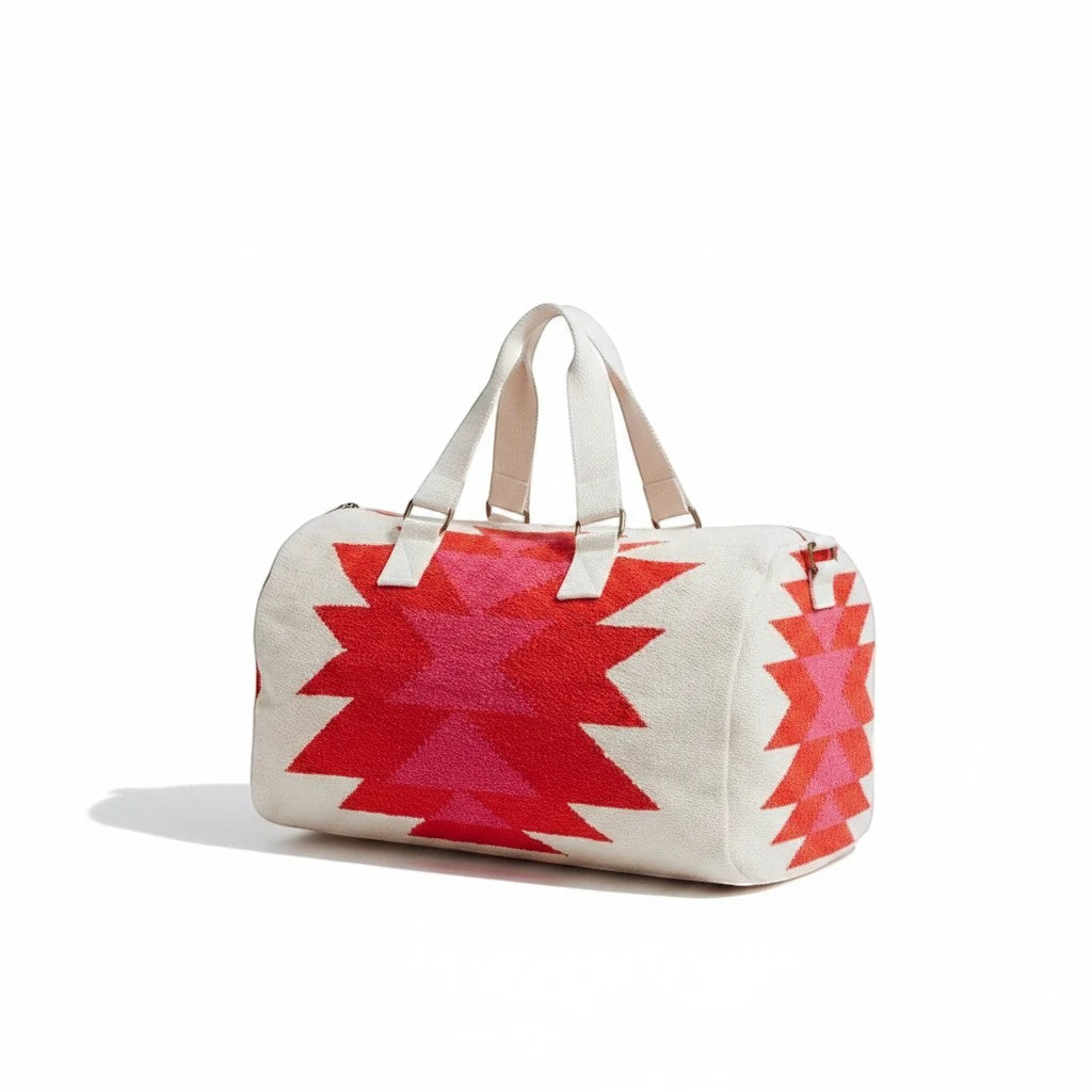 Sighthound Designs cream duffel bag with red and pink geometric pattern and white straps.
